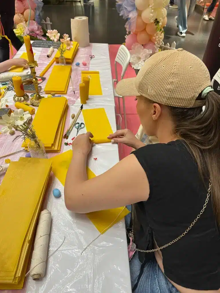 Animation commerciale : pourquoi le contact humain reste un levier gagnant Participante roulant une bougie en cire d'abeille pendant un atelier d'animation commerciale en centre commercial