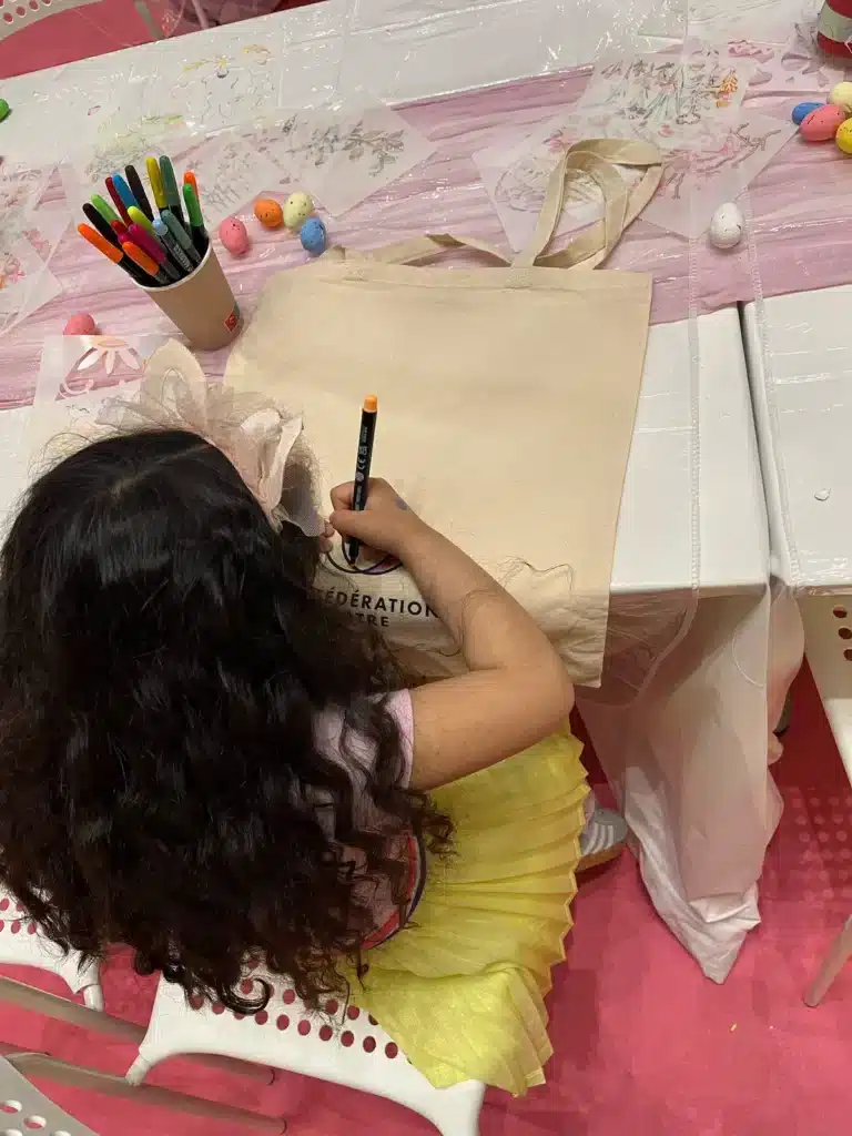 Animation commerciale : pourquoi le contact humain reste un levier gagnant Enfant personnalisant un tote bag au feutre lors d'un atelier créatif en animation commerciale