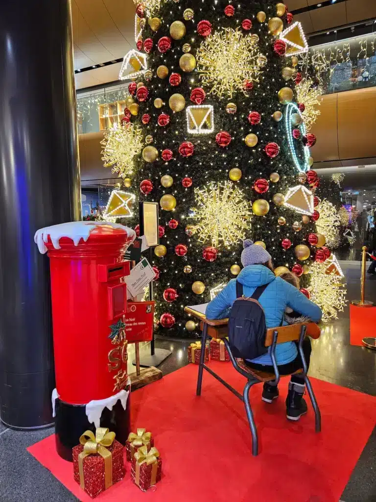 Animation commerciale : pourquoi le contact humain reste un levier gagnant Animation commerciale de Noël en centre commercial avec sapin décoré et boîte aux lettres du Père Noël