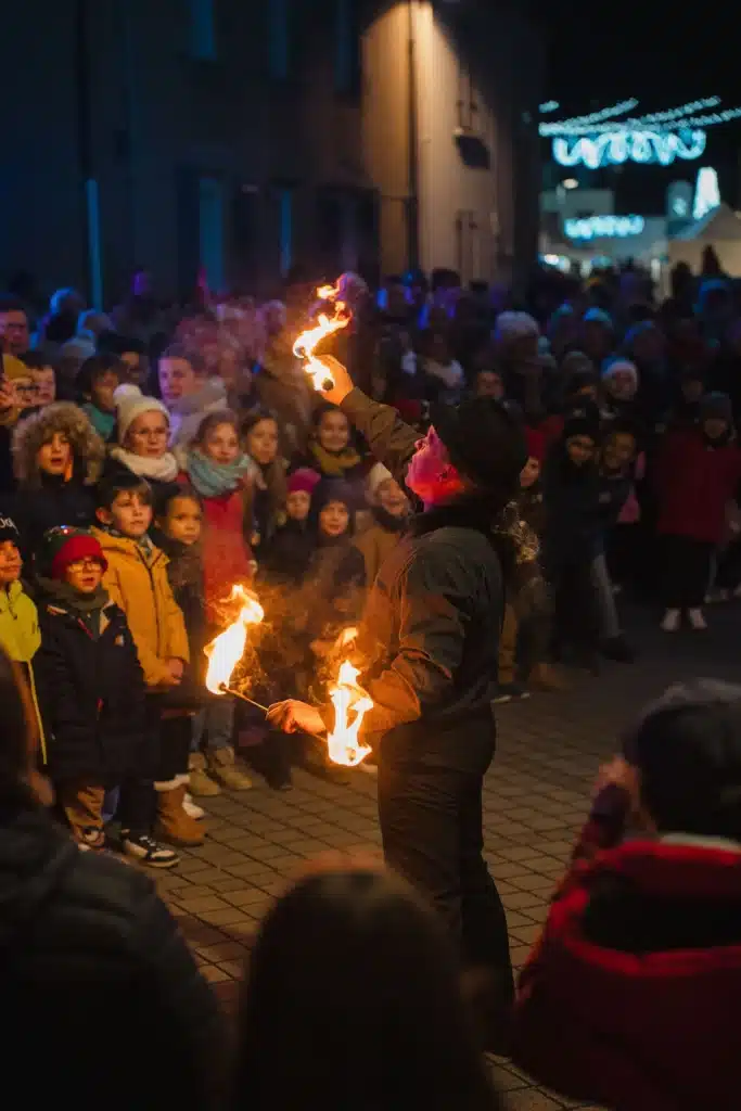 Spectacle de jongleur de feu devant un public d'enfants et d'adultes lors d'un événement de fin d'année